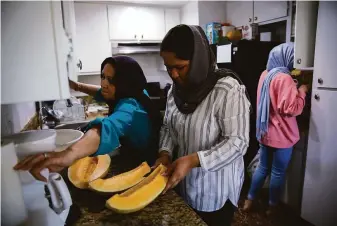  ?? Photos by Yalonda M. James / The Chronicle ?? Lailama Saeedi (left) prepares to serve melon to arriving relatives with her 16-year-old twin daughters, Sapeidah (center) and Ghazal, at the family’s apartment in Sacramento.