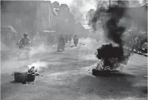  ?? ?? Motorcycle­s ride past a barricade of burning tires during a protest by residents in downtown Port-au-prince, Haiti. Violence can break out at any time, in any random corner of the city, where many Haitian migrants deported from the United States were sent.