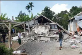  ?? ROSIDIN — THE ASSOCIATED PRESS ?? Villagers walk near destroyed homes in an area affected by the early morning earthquake at Sajang village, Sembalun, East Lombok, Indonesia, Sunday. A shallow, magnitude 6.4 earthquake early Sunday killed at least 10 people and injured 40 on...