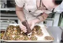  ??  ?? A kitchen staffer prepares appetizers in the kitchen of the Pineapple and Pearls restaurant. — AFP photos