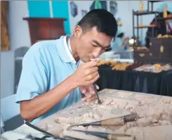  ??  ?? A woodworker in Kunming displays his carving skills at an exhibition.