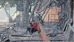  ?? | MOHAMMED ABED AFP. ?? PALESTINIA­N men sit amid debris in the Hamas-controlled Gaza Strip, after an Israeli air strike, in Gaza City this week.