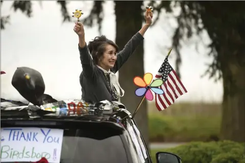  ?? LAUREN A. LITTLE — MEDIANEWS GROUP ?? Christine Sandritter of Exeter Township rings bells as she hangs out of her car’s sunroof while parading by the Birdsboro Lodge personal care home. She was there to cheer for her mother, Vangie, a resident of the home. Her husband Bryan Sandritter is driving the car.