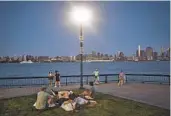  ?? ANDRES KUDACKI AP FILE ?? People hang out at a park at dusk on July 21 during a heat wave in Hoboken, N.J.