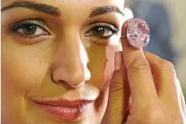  ??  ?? Twinkle, twinkle: A Sotheby’s employee holding up the Pink Star diamond during a preview at Sotheby’s in Geneva. — AP