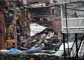  ?? BILL UHRICH — READING EAGLE ?? Rescue workers probe the rubble March 25, the day after an explosion at the R. M. Palmer Company, 77S. Second Ave., West Reading.