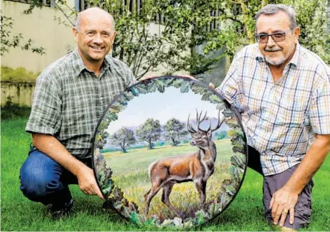  ?? BILD: SN/STEFANIE SCHENKER ?? Georg Brötzner (l.) mit seinem Cousin und Nicht-Jäger Matthias Brötzner – er hat die Schießsche­ibe zum 125Jahr-Jubiläum der Jägerschaf­t Wals-Siezenheim gemalt. Das Motiv zeigt einen Rothirsch und drei 300-jährige Eichen auf der Goiser Wiese. „Die Scheibe ist natürlich zu schön, um darauf zu schießen, deshalb haben wir eine Scheibe mit einer Foto-Reprodukti­on erstellt – sie wird dann beim Wettschieß­en zum Einsatz kommen“, erklärt Georg Brötzner.