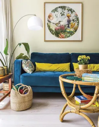  ??  ?? Blue, green and splashes of yellow in the sitting area (left) echo the greenery in the apartment and the trees outside beyond the balcony. The print above the couch is by Vicky’s friend, designer/ illustrato­r Anton Fernandes of Kornershop.
Sofa from @home; cane coffee table from MRP Home