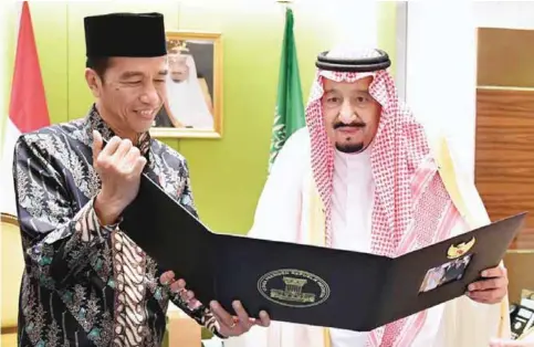  ?? — AFP ?? JAKARTA: Indonesia’s President Joko Widodo (left) presents a photo album with images from their meeting in Bogor the day before to Saudi Arabia’s King Salman bin Abdul Aziz yesterday.