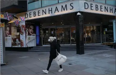  ?? (AP/Matt Dunham) ?? A woman wearing a mask walks past the Debenhams flagship department store on Oxford Street in London last week during England’s second coronaviru­s lockdown.