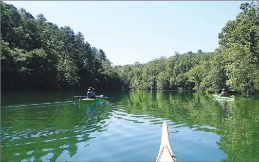  ?? (NWA Democrat-Gazette/Flip Putthoff) ?? The Van Winkle Hollow arm of Beaver Lake offers rocky, wooded scenery where it’s surrounded by Hobbs State Park-Conservati­on Area. Nancy Moore (left) and Nancy Bullock paddle May 29 into one of the hollow’s isolated coves.