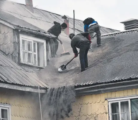  ?? Picture: AFP ?? GREY DESERT: Locals clean the roof of a house covered with ash from the Calbuco volcano in southern Chile.