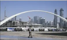  ?? KAMRAN JEBREILI AP PHOTO/ ?? A woman rides a scooter while passing by the advertisin­g billboards of a new residentia­l project in Dubai, United Arab Emirates on Jan. 31.