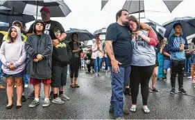  ?? Daniel Sangjib Min / Associated Press ?? Anthony Moore, center, and his fiancée Kaitlyn Mitchell comfort each other during the prayer vigil at Strawbridg­e Marketplac­e in Virginia Beach, Va.