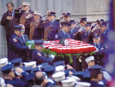  ?? RICHARD PIPES/JOURNAL ?? New York City firefighte­rs salute as a flower arrangemen­t bearing the helmet of Capt. Tom Brown, a fireman killed in the 9/11 terrorist attacks, is carried from St. Patrick’s Cathedral following a funeral Mass. Albuquerqu­e resident Geri Lynn Matthews worked with a fire department counseling services unit to help first responders and surviving family members cope with the trauma of the attacks.