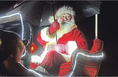  ?? PHOTOS: MIKE ZETTEL PORT COLBORNE LEADER ?? Santa Claus comes prepared for the weather for Saturday night’s parade in his honour in Port Colborne. While rain held off for most of the evening, it came down fairly heavy towards the end.