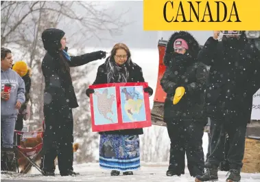  ?? CHRIS HELGREN/REUTERS ?? A woman holds maps as First Nations members of the Tyendinaga Mohawk Territory block train tracks servicing Via Rail, as part of a protest against British Columbia’s Coastal GasLink pipeline, in Tyendinaga, Ont., on Thursday.