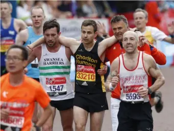  ?? (AFP/Getty) ?? Swansea Harrier Matthew Rees helps struggling runner David Wyeth cross the finish line