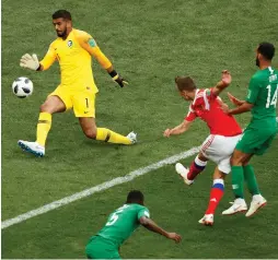  ?? (Reuters) ?? RUSSIA MIDFIELDER Denis Cheryshev (in red) scores his team’s second goal – his first of two in the match – against Saudi Arabia ’keeper Abdullah Al Muaiouf in a 5-0 victory over the Saudis in last night’s World Cup opener in Moscow.