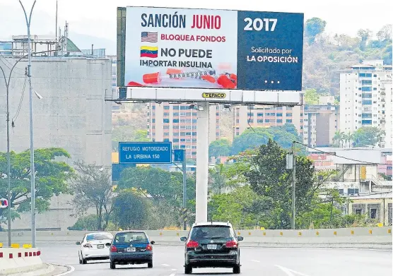  ?? JUAN BARRETO/AFP ?? Un cartel sobre una autopista en Caracas critica a la oposición venezolana por las sanciones vigentes