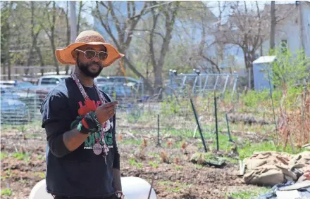  ?? MORGAN HUGHES / MILWAUKEE JOURNAL SENTINEL ?? Kenneth Brown Jr., a community organizer in Harambee, shows an example of the fresh spinach plants growing in Victory Garden Initiative’s urban farm.
