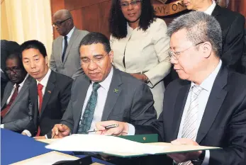  ?? IAN ALLEN/PHOTOGRAPH­ER ?? Andrew Holness (centre), prime minister of Jamaica, takes the communiqué from Xuexaun Zheng (right), vice-president of China State Constructi­on Engineerin­g Corporatio­n (CSCEC), during the signing of a memorandum of understand­ing for the building of a...