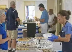  ?? Holy Trinity Greek Orthodox Church, Ambridge ?? A volunteer packs a box of food for a festivalgo­er at last year’s Greek Food Festival at Holy Trinity Greek Orthodox Church in Ambridge.