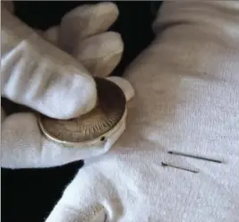  ?? JACQUELYN MARTIN, THE ASSOCIATED PRESS ?? H. Keith Melton holds a silver dollar with a hole for a hidden suicide pin, right, one of Melton’s donations to the Internatio­nal Spy Museum from his collection of spy objects.