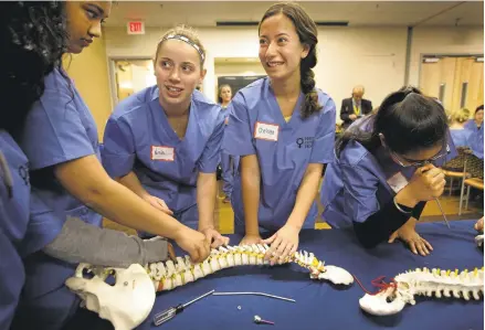  ?? PATRICK TEHAN/STAFF PHOTOS ?? High school girls learn to drill into and repair fractured bones during a workshop put on by the Perry Initiative's outreach program at the Kaiser Permanente Santa Clara Medical Center.