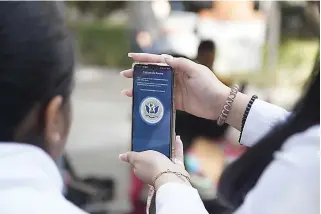  ?? (Alejandro Tamayo/the San Diego Union-tribune) ?? An official assists a migrant with the use of the CBP One app on Jan. 12 at Palacio Municipal in Tijuana, Baja California.