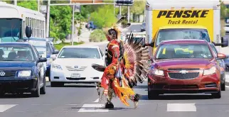 ??  ?? ABOVE: Shawn Hudson of Colorado Springs crosses the street on his way to participat­e in the Grand Entrance at the 29th Gathering of Nations Pow Wow at the Pit in 2012.