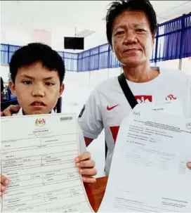  ??  ?? Please help me: Jia Yi (left) showing his birth certificat­e, which shows that he is not a citizen as his father Ban Guan holds his son’s applicatio­n for citizenshi­p which he submitted at the NRD in Taiping.