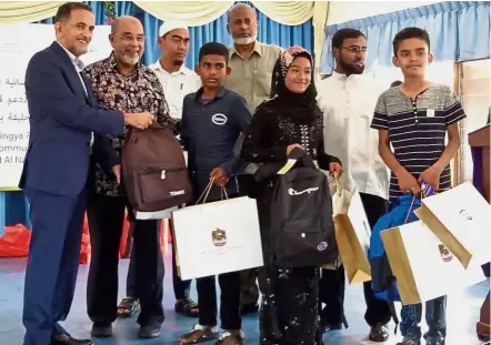  ?? Good cause: ?? UAE Ambassador to Malaysia Khalid Al- Ghaith (left) and Syed Hamid (second from left) handing out school bags and uniforms to some of the Rohingya children at their school in Ampang, Kuala Lumpur.