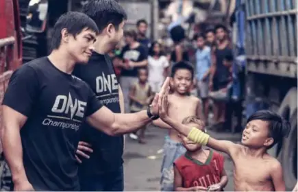  ?? ONE Championsh­ip photo ?? UP HERE. Former One Championsh­ip lightweigh­t world champion Eduard Folayang high fives a child in Tondo during an outreach activity that saw ONE Championsh­ip athletes visit youth living in Manila in partnershi­p with non government organizati­on Young...