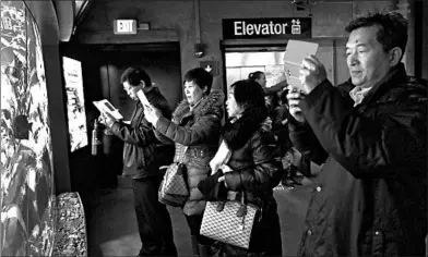  ?? ELISE AMENDOLA/AP 2017 ?? Tourists from China take photos at a Boston aquarium. The coronaviru­s is keeping millions from leaving China.