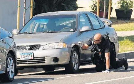  ?? Wally Skalij Los Angeles Times ?? A MEMBER of the LAPD bomb squad inspects the Nissan Sentra of UCLA shooter Mainak Sarkar in Culver City. Inside, police found a handgun and several red cans of gasoline. Authoritie­s say Sarkar drove from Minnesota, parked the car and took a bus to UCLA.