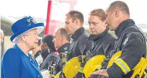  ?? Picture: PA. ?? The Queen meets firefighte­rs during a visit to the Westway Sports Centre, London, which is providing temporary shelter.