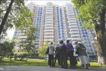  ?? PHOTO VIA AP ?? People look at a the apartment building in Moscow, Russia, damaged by a drone in an attack that authoritie­s blamed on Ukraine on Tuesday.