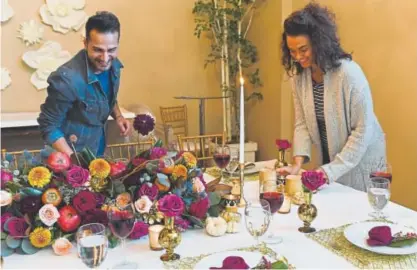  ?? John Leyba, The Denver Post ?? Myisha McCarthy, right, and Saif Ibrahim set a Thanksgivi­ng table at Newberry Brothers Florist that draws from what McCarthy calls “jewel-tone fall colors” rather than traditiona­l shades of red and orange.