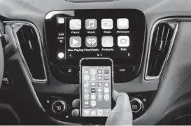  ?? Paul Sancya / Associated Press ?? An iPhone is connected to a 2016 Chevrolet Malibu equipped with Apple CarPlay apps, displayed on the car’s MyLink screen, top, during a demonstrat­ion.