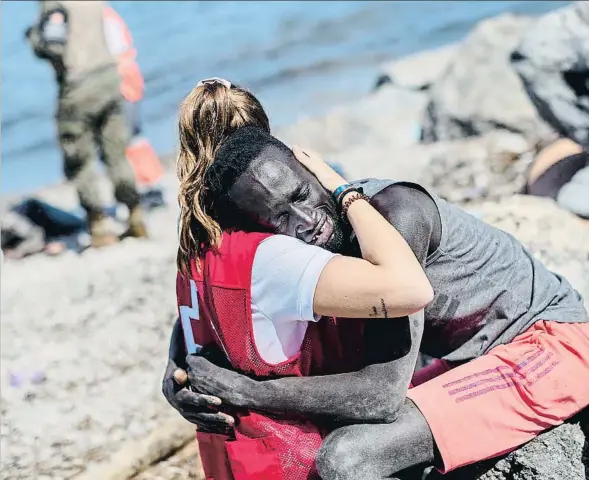  ??  ?? Una voluntària de la Creu Roja atén un migrant africà a la platja d’El Tarajal, a Ceuta