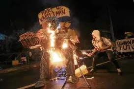  ?? —GRIG C. MONTEGRAND­E ?? PROTEST PROP An activist burns an effigy of President Duterte during a rally at the foot of Don Chino Roces Bridge in Manila on Tuesday night.