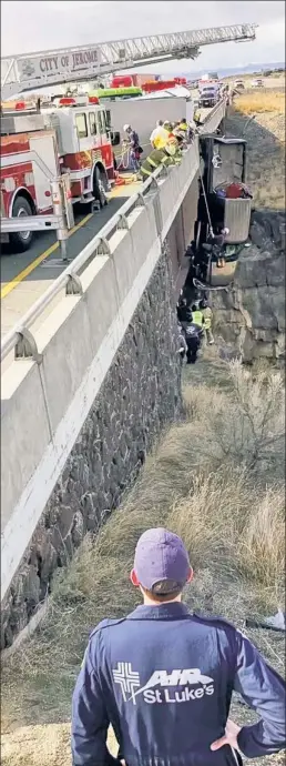  ??  ?? A REAL GORGE-HANGER: A pickup truck carrying an Idaho man and woman plus their two dogs hangs by its trailer-towing chain over a 100-foot gorge before fast-acting rescuers (inset) rappel down and lift all to safety.