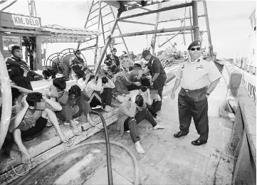  ??  ?? Shahref (right) and MMEA personnel with the detained Vietnamese fishermen.