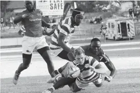  ??  ?? Zimbabwe flank Connor Pritchard puts down Zimbabwe’s third try, under challenge from Kenya’s David Ambunya, during the Sables 22-41 loss at Hartsfield in this file photo