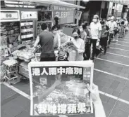  ?? VINCENT YU/AP ?? A woman in June tries to take a picture of the last issue of Apple Daily, the pro-democracy paper in Hong Kong that eventually folded under Beijing’s pressure.