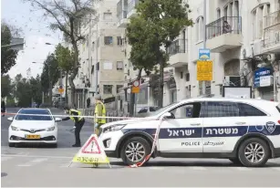  ?? (Marc Israel Sellem/The Jerusalem Post) ?? A POLICEMAN stops a car at a checkpoint on Strauss Street in Jerusalem outside Mea She’arim yesterday.