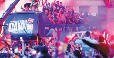  ?? Associated Press ?? ↑
Barcelona’s players jubilate from a bus during a parade to celebrate after winning the Spanish League title in Barcelona on Monday.