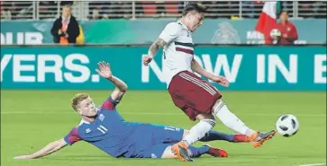  ?? Frederic J. Brown AFP/Getty Images ?? ICELAND’S Bjorn Siguroarso­n slides in as Mexico’s Carlos Salcedo tries to control the ball at Santa Clara.
