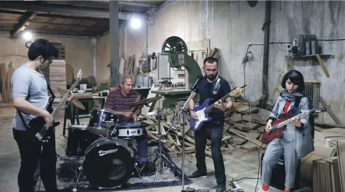  ??  ?? Afghan musicians Mohammad Rezai, left, Hakim Ebrahimi, second right, and Soraya Hosseini, right, members of the Arikayn rock band, along with Kourosh Ghasemi, an Iranian drummer, play music at a furniture workshop in Eslamshahr, outside Tehran, Iran. Like others in Iran's vibrant arts scene, Afghan musicians must contend with hard-liners who view Western culture as corrupt and object to women performing in public